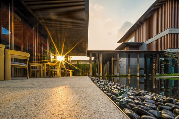 Un bâtiment moderne doté d’un bassin décoratif et d’un espace aménagé pour s’asseoir.
