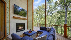 Una terraza con mobiliario exterior, chimenea y televisor en la pared.