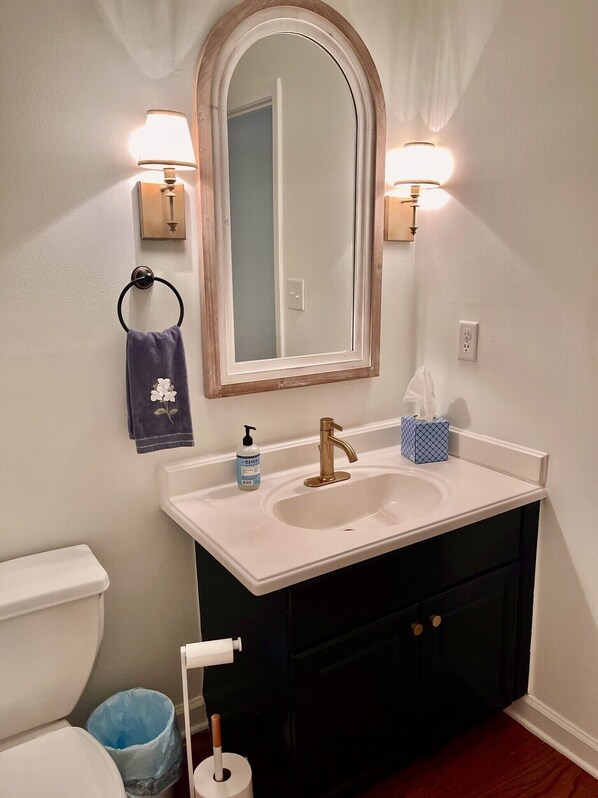 A bathroom with a white sink, a gold faucet, a mirror with a wooden frame, and two wall-mounted lights. - Spectacular 3 BDR Townhouse Near Downtown ATL, GSU (Atlanta)
