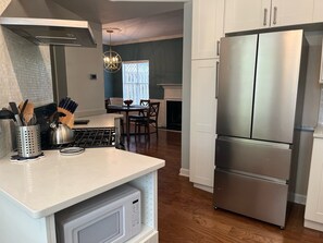 A modern kitchen with a stainless steel refrigerator, a microwave, and a gas stove. - Spectacular 3 BDR Townhouse Near Downtown ATL, GSU (Atlanta)