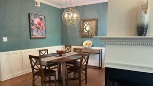 A dining room with a wooden table, chairs, a chandelier, a fireplace, and wall art. - Spectacular 3 BDR Townhouse Near Downtown ATL, GSU (Atlanta)
