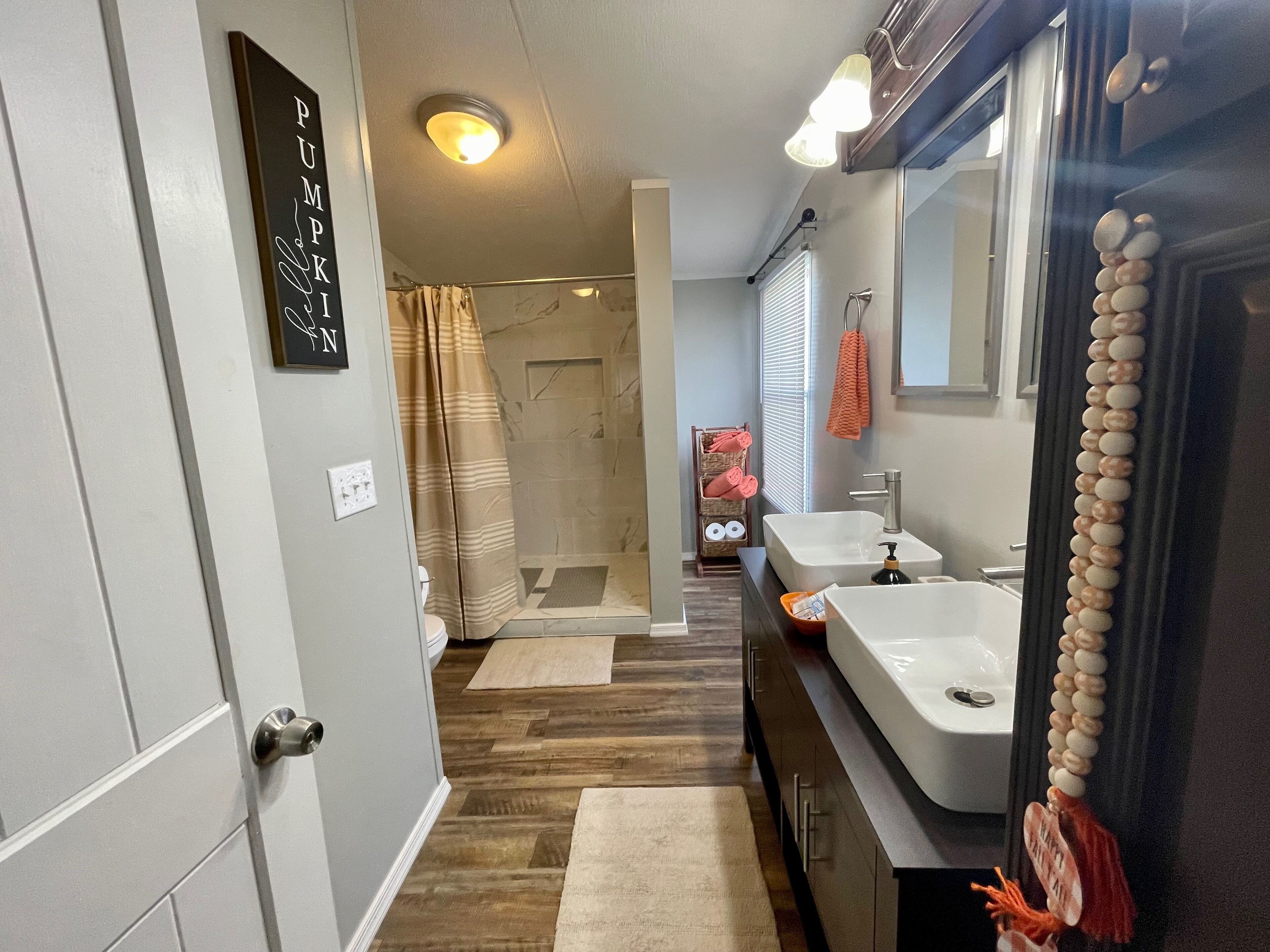 A modern bathroom with a shower, two sinks, a toilet, and a vanity with a mirror.