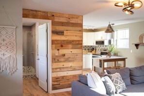 A modern kitchen with wooden accents, a dining area with a table and chairs, and a gray sofa with patterned cushions. - Lovely Strip District loft with free parking (Pittsburgh)