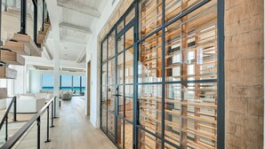 Un interior moderno con suelo de madera, una escalera y un amplio muro de cristal con listones de madera.