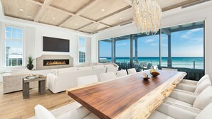 Un amplio salón con una gran mesa de comedor de madera, sofás blancos y una chimenea.