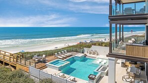 Un resort moderno con piscina, vistas a la playa y zona de estar al aire libre.