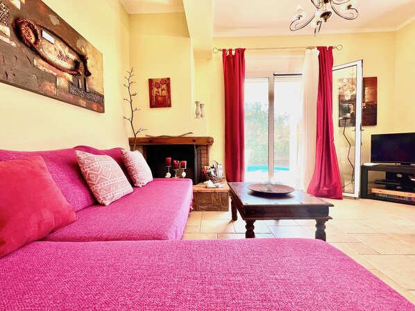 A cozy living room with a fireplace, a sofa, a coffee table, and a TV. - Beach Villa Iolis with private pool (Lefkada)