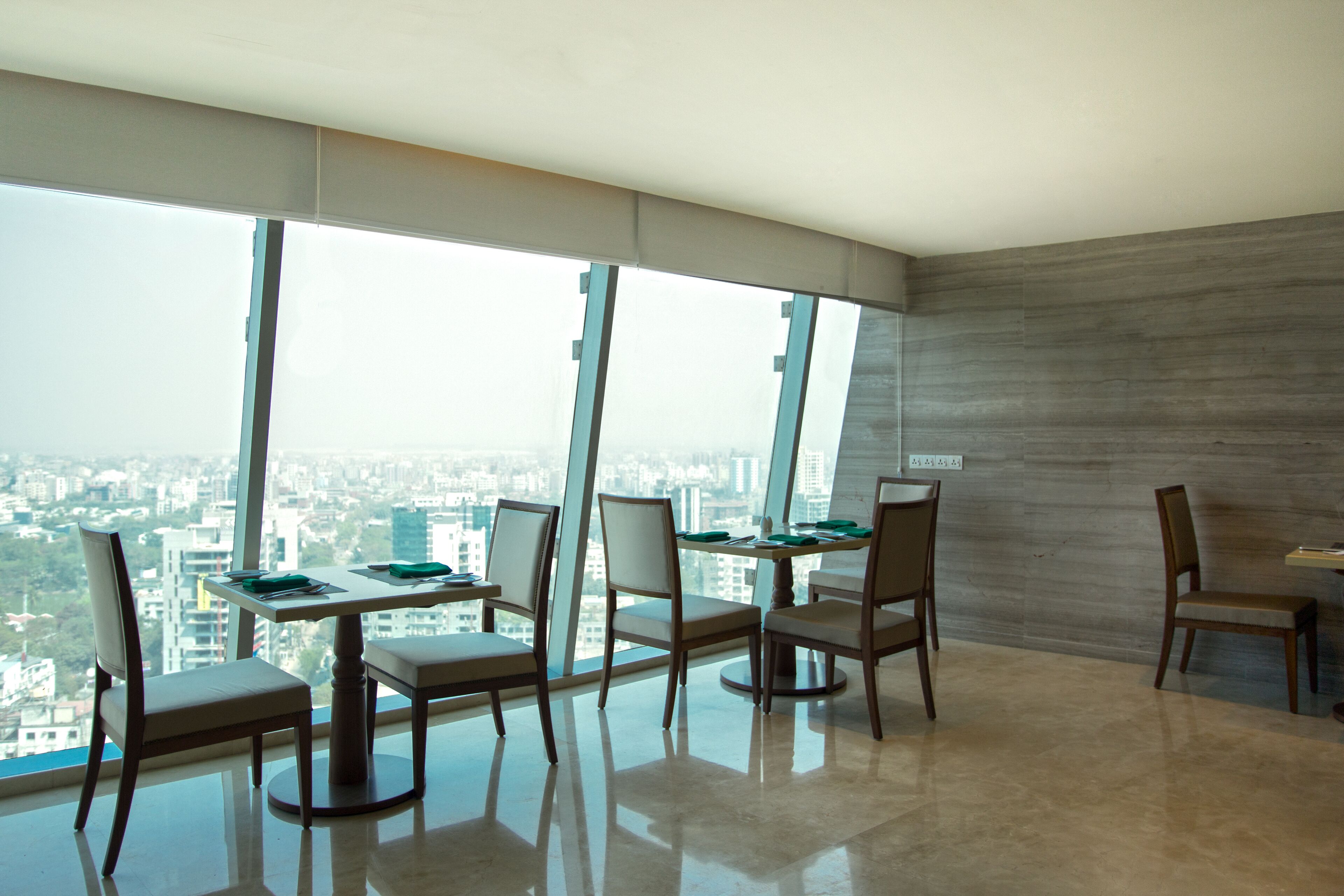 A modern dining area with a city view, large windows, and a minimalist design.