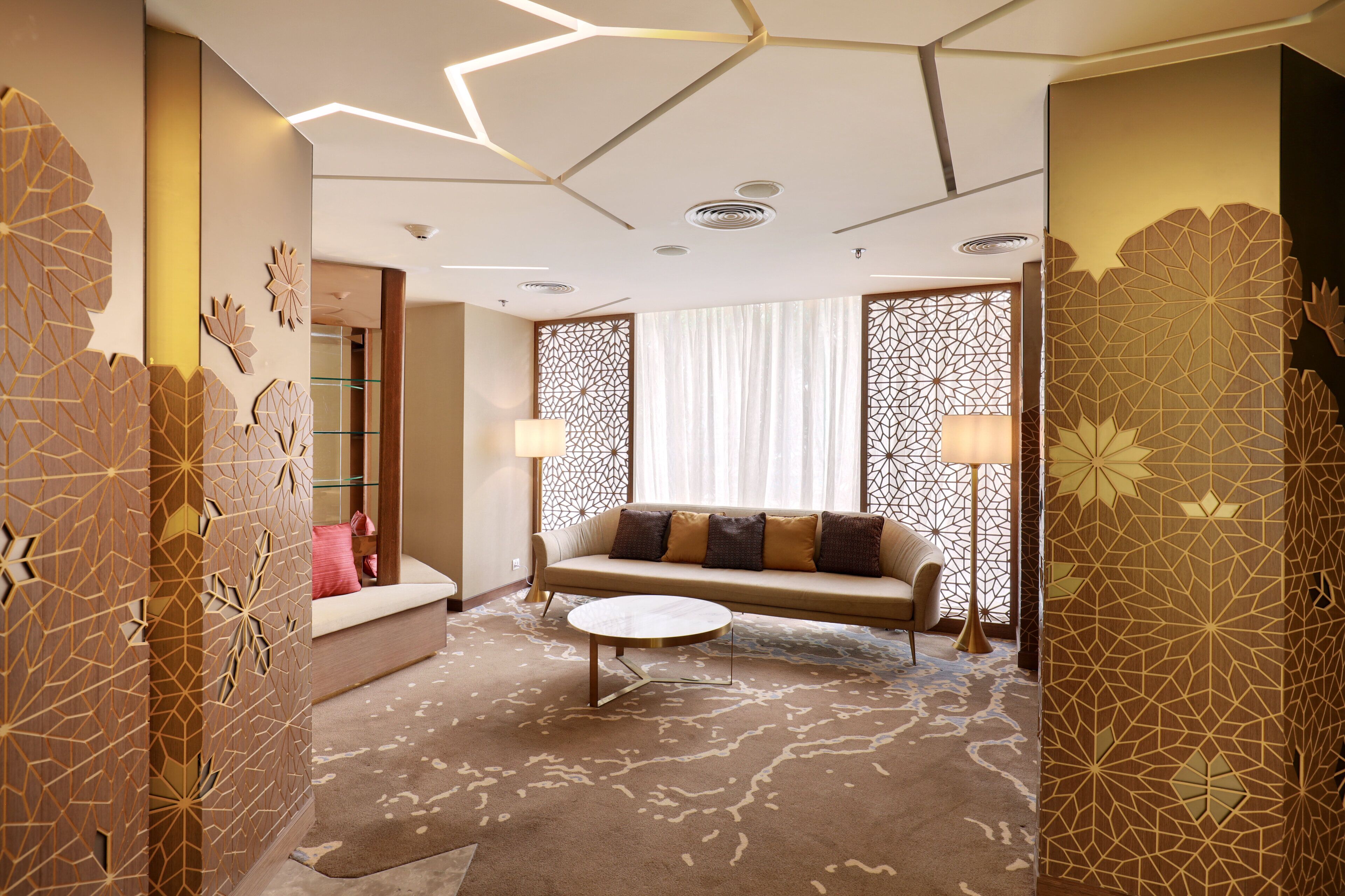 Une chambre d’hôtel moderne, dotée d’un canapé, d’une table basse ronde et de panneaux décoratifs.
