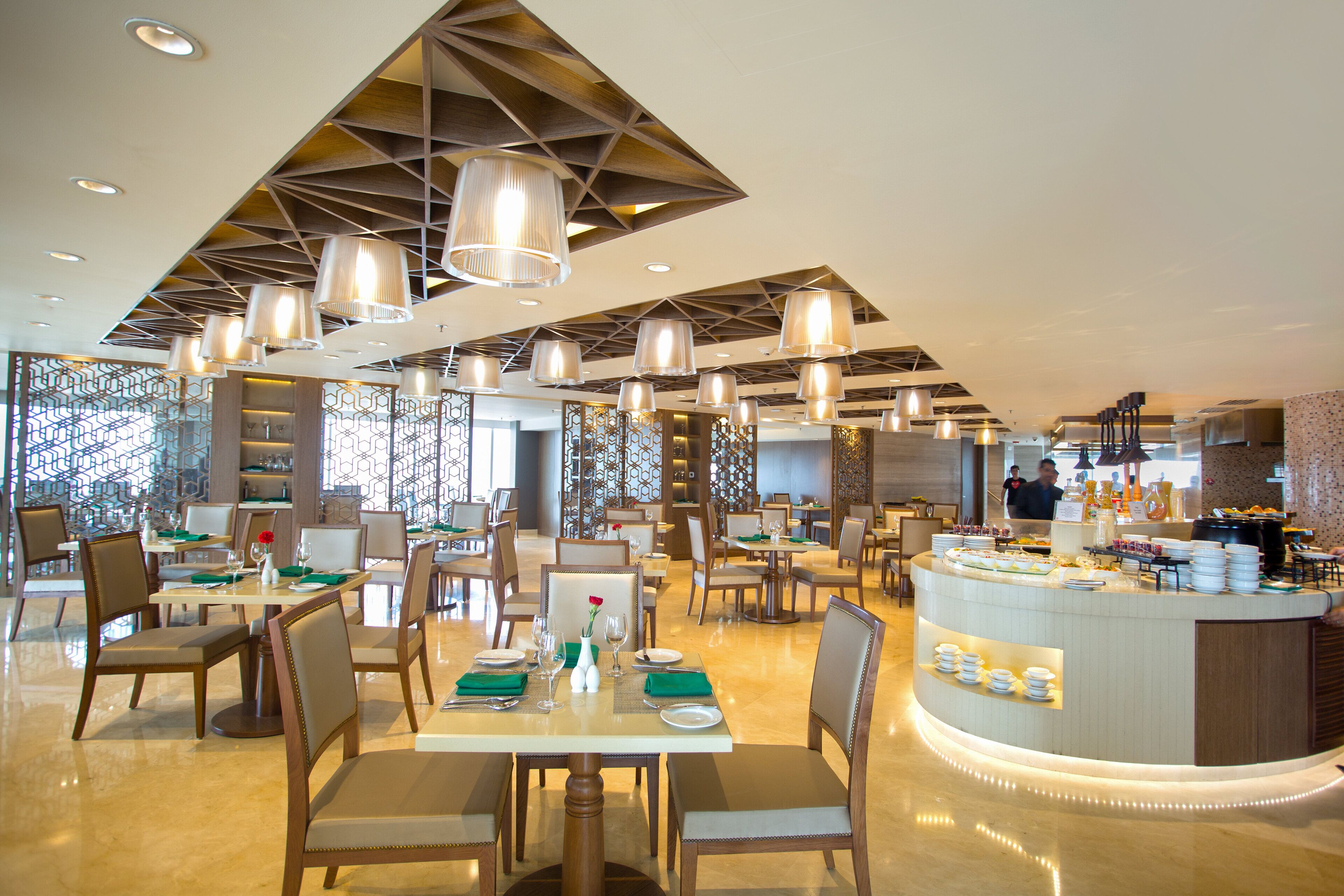 A modern restaurant with multiple dining tables, chairs, and hanging pendant lights.