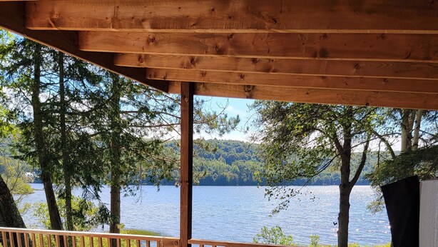 A hot tub with a wooden deck and a view of a lake. - the Laurentides Private Log and Spa Escape (Rivière-Rouge)