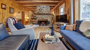 A cozy living room with a stone fireplace, leather sofas, a television, and a Christmas tree. - the Laurentides Private Log and Spa Escape (Rivière-Rouge)