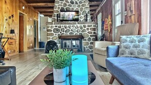 A cozy cabin interior with a stone fireplace, wooden ceiling, and a comfortable seating area. - the Laurentides Private Log and Spa Escape (Rivière-Rouge)