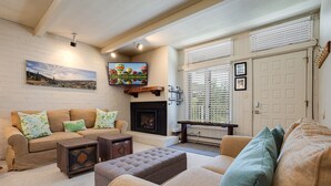A living room with a fireplace, a sofa set, a television, and a window with blinds. - ST309 | Across the Street from Slopes | Hot Tub | Great location | Free City Bus (Steamboat Springs)