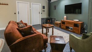 Un salon comprenant un canapé, une table basse, un téléviseur, une cheminée et un meuble en bois.