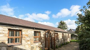 Un bâtiment en pierre doté de nombreuses fenêtres et d’une terrasse carrelée.