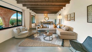 Una sala de estar moderna con un sofá, dos sillones, una mesa de centro y un comedor al fondo.