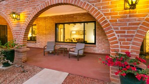 Un edificio de ladrillo con entradas arqueadas, un patio con asientos y un interior bien iluminado visible a través de amplios ventanales.