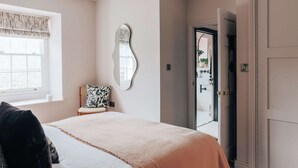 Ein Schlafzimmer mit einem Bett, einem Sessel, einem Spiegel und einer Tür zum Badezimmer.