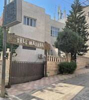 Entrada de un hotel con un letrero que dice 'TELM MADABA HOTEL'.