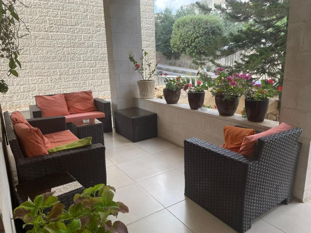 Un espacio de descanso al aire libre con mobiliario de mimbre y plantas en macetas.