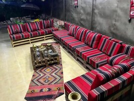 Una sala de estar con un sofá de estilo moderno a rayas rojas y negras, una mesa de centro con objetos decorativos y una alfombra estampada.