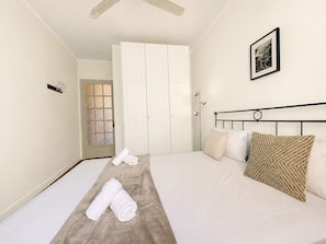A bedroom with a bed, a door, a towel, and a picture on the wall.