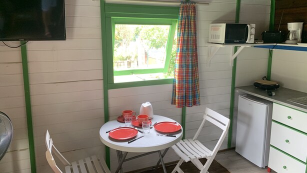 A small kitchen with a dining table, chairs, a microwave, and a refrigerator. - Bungalow for 2 persons (Les Trois-Îlets)
