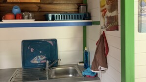 A kitchen with a sink, a blue dish rack, and a hanging towel. - Bungalow for 2 persons (Les Trois-Îlets)