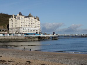 A large hotel with multiple stories and a prominent tower, located near a pier extending into the water. - Apartment 2 (Llandudno)