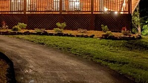 A wooden cabin with a covered porch, a dirt path leading to it, and string lights along the roof. - Private Cabin Retreat – Relax in the Hot Tub & Cozy Up by Fire! (Pigeon Forge)