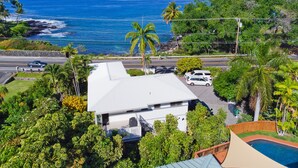 A residential area with a view of the ocean, a swimming pool, and a white house with a covered patio.