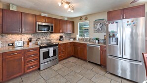 A modern kitchen with wooden cabinets, stainless steel appliances, and a tiled backsplash.
