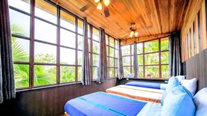 A room with large windows, wooden ceiling, and two beds with blue and white bedding. - Jungleland at Hermosa Point. 2 Pools, A/C & Wi-Fi! Sleeps 23!
Rustic Luxury! (Playa Hermosa)