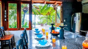 A kitchen with a long counter, blue bowls, glasses of orange juice, and a bowl of oranges. - Jungleland at Hermosa Point. 2 Pools, A/C & Wi-Fi! Sleeps 23!
Rustic Luxury! (Playa Hermosa)