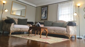 A living room with a floral sofa, a wooden coffee table, a large mirror, and a framed picture on the wall. - Cozy & Quiet beautiful 4 bedrooms , close to downtown, Cleve clinic  (Parma)