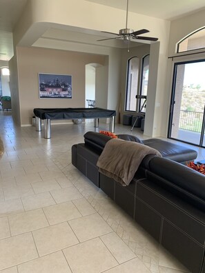A modern living room with a pool table, a large sofa, and a ceiling fan. - Super bowl & Phoenix Open Week -Mountain Views,Infinity Pool (Fountain Hills)