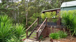 A wooden staircase leading to a green-roofed building surrounded by lush greenery and trees. - Refreshing Rainforest Retreat - Kangaroo Valley (Kangaroo Valley)