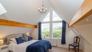 Ein Schlafzimmer mit einem großen Bett, einem Holzbalken an der Decke, einem Fenster mit Blick und einem Sessel.