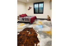 A bedroom with a bed, a rug, and a cowhide rug.
