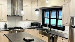A modern kitchen with a central island, stainless steel appliances, and pendant lighting. - Bear Creek Lodge (Dorchester)