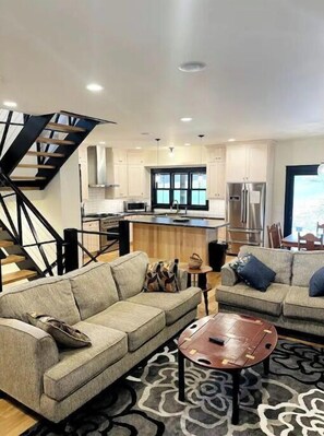 A modern living room with two sofas, a coffee table, and a staircase.