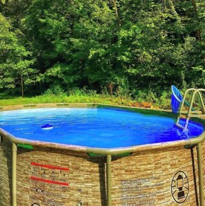 Enjoy a refreshing swim surrounded by lush greenery and access the pool via the attached ladder.