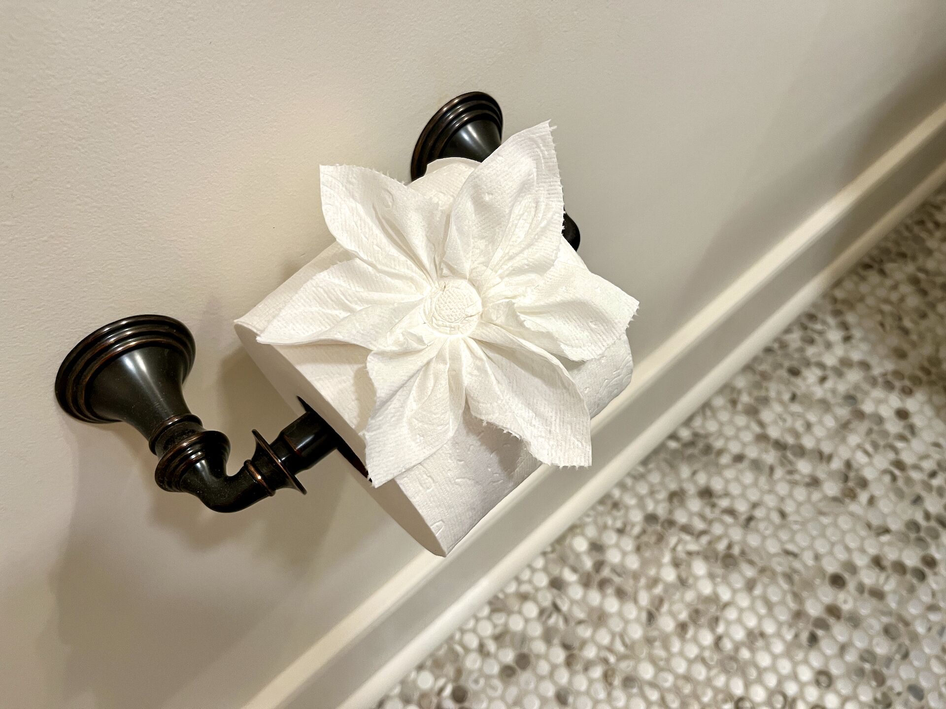 A toilet paper holder with a decorative paper towel on it.