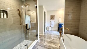 Ein modernes Badezimmer mit einer gläsernen Duschkabine, einer Badewanne und einem Waschtisch.