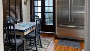 A dining area with a table and chairs, a ceiling fan, and a refrigerator.