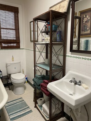 Une salle de bain équipée de toilettes, d’un lavabo et d’étagères où sont rangés les articles de toilette.