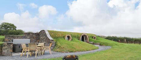 A stone building with a grassy hill, outdoor seating, and a fire pit.