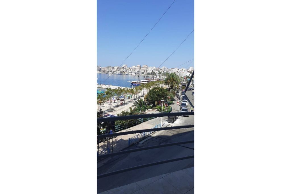 Un paisaje urbano costero con un puerto deportivo, edificios y una línea de teleférico.