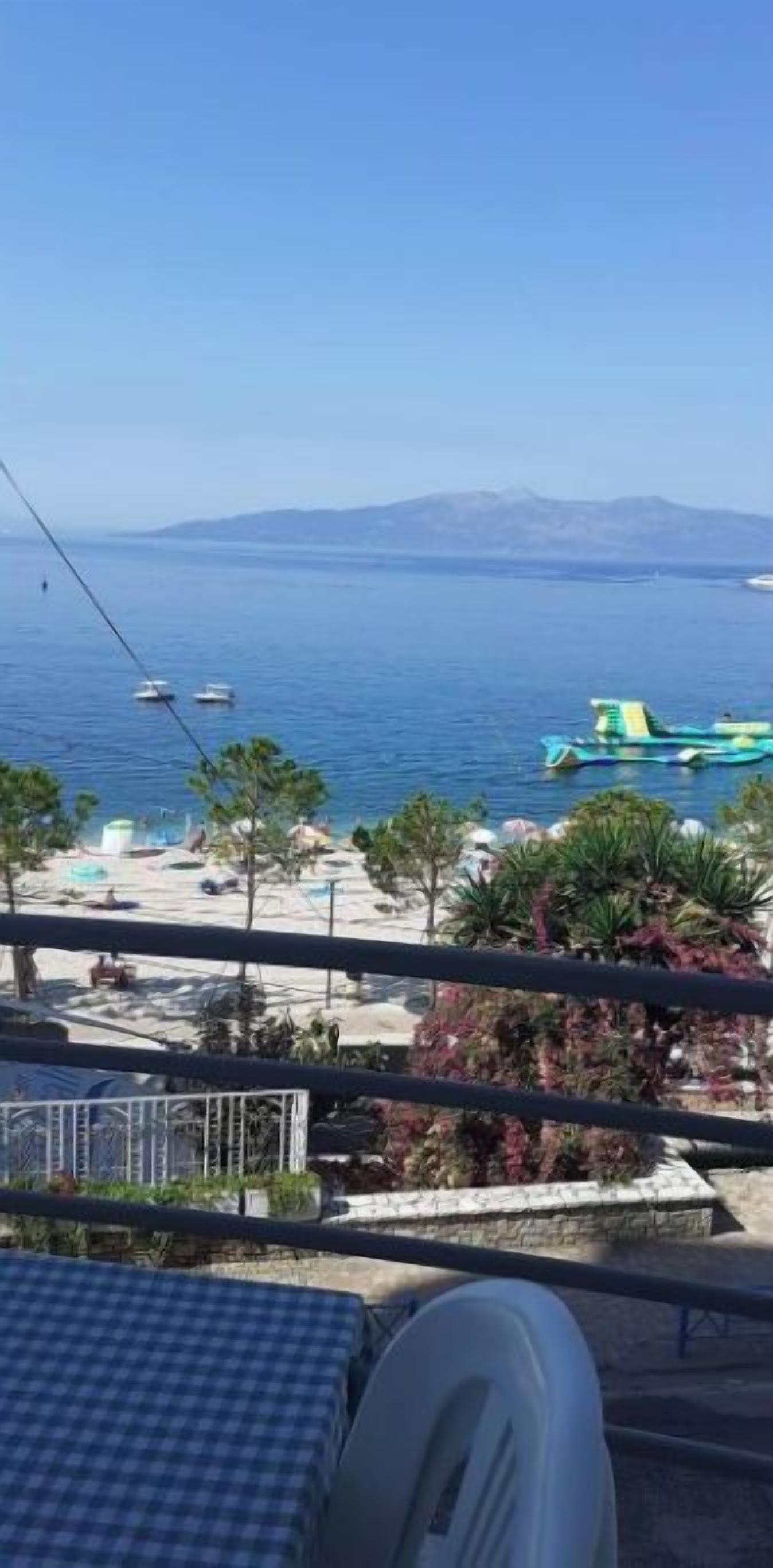 A balcony with a view of the sea, a beach, and a mountain in the distance.